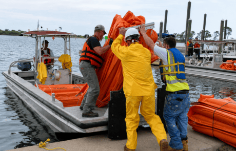 Oil Containment Boom Loading for Marine Spill Response Emergency response crew loading orange oil containment boom onto a work boat for marine oil spill response and waterway protection.