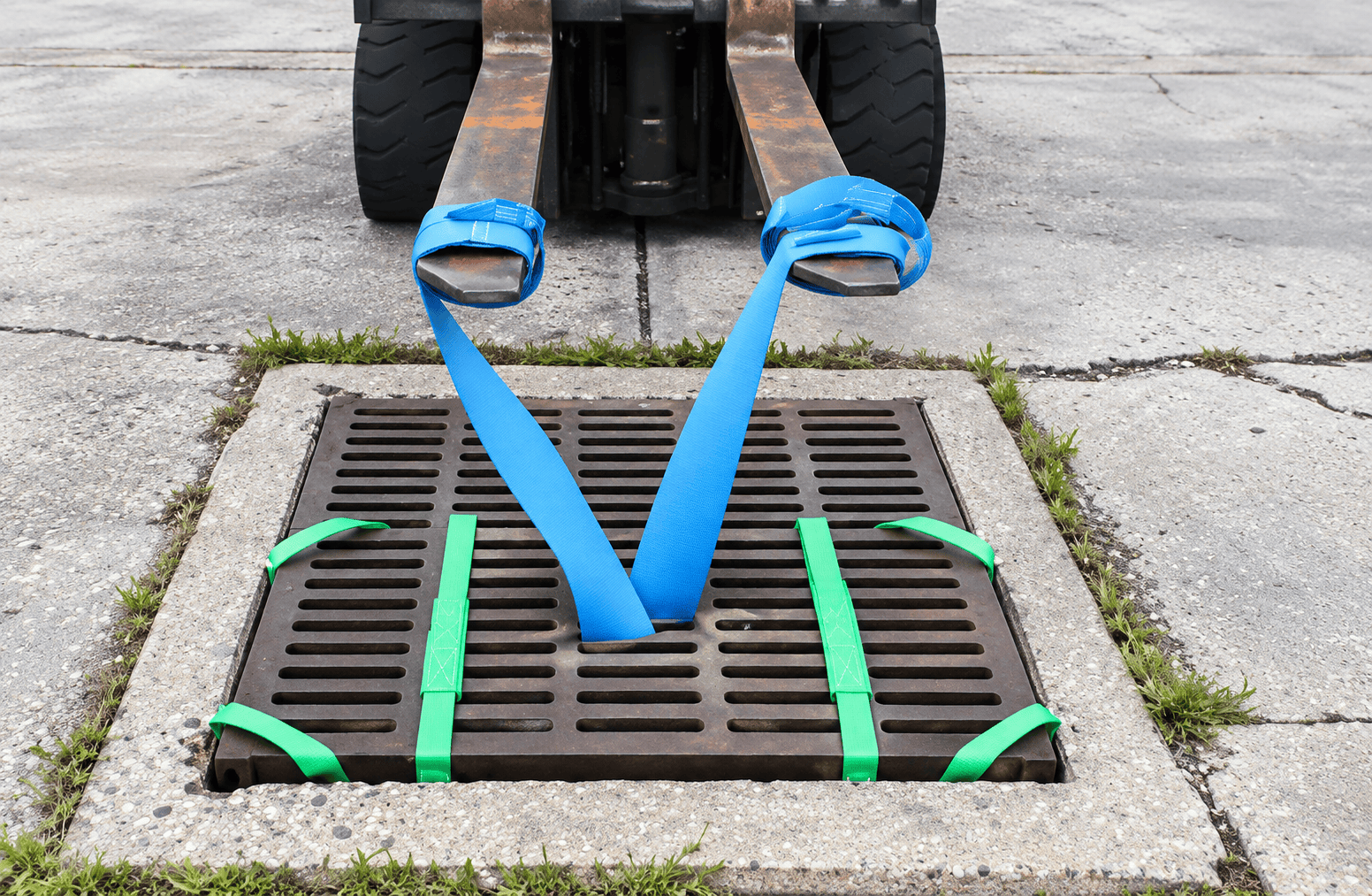 Replacing Storm Drain Grate Over Under-Grate Inlet Protection Filter Forklift replacing a storm drain grate over an installed under-grate inlet protection filter secured with green webbing straps for stormwater sediment control.